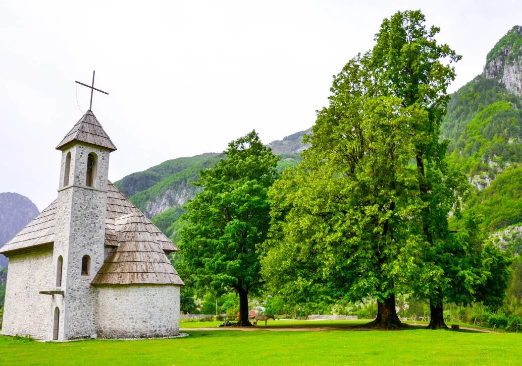 Theth valley in late spring, Albania — green meadows, snow-capped Albanian Alps peaks, and the Shala River after snowmelt
