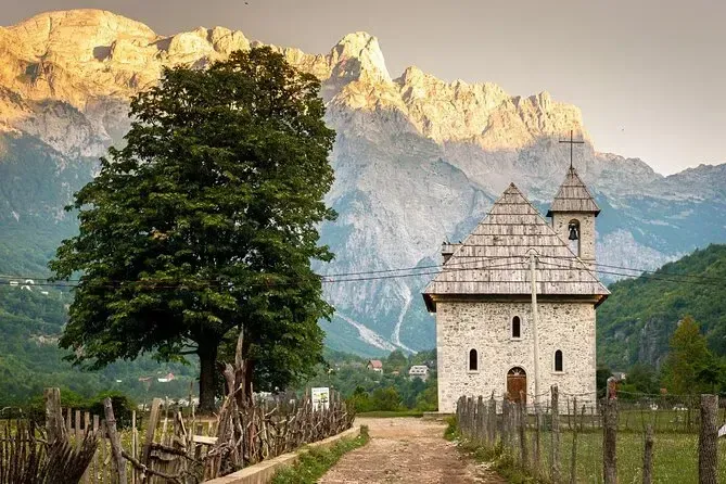 The historic church in Theth village, set against the snow-capped peaks of the Albanian Alps